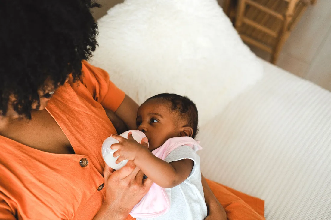Eine Bezugsperson füttert ein Baby mit dem Fläschchen.