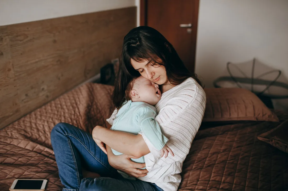 Eine Mutter sitzt und hält ihr Baby auf dem Arm.